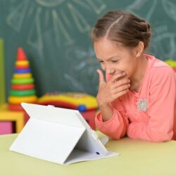 Girl Student Smiling While Viewing Tablet At Table