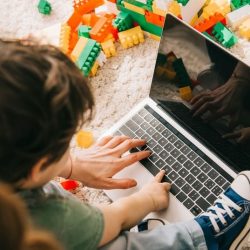 Mother And Small Child Using Laptop On The Ground With Toy Blocks Around Them