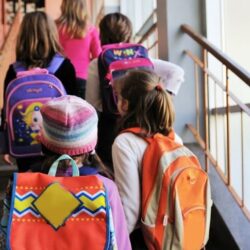 Group Of Girl Students Walking Up Stairs With Colorful Backpacks