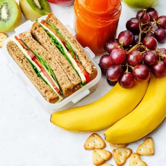 Sandwich, Bananas,and Grapes On White Table