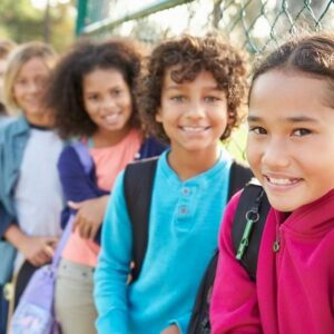 Group Of Students Smiling While Leaning On A Gate