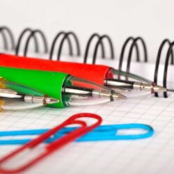 Colorful Pens Lying On Notebook With Paper Clips