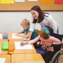 Female Teacher Helping Students At Table