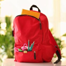 Red Backpack With School Supplies Visible In Pocket